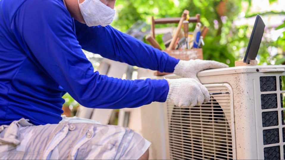 AC technician servicing an outdoor air conditioning condenser unit at a Dubai villa