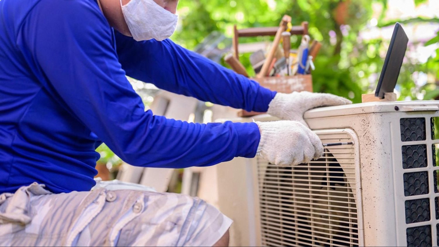 AC technician servicing an outdoor air conditioning condenser unit at a Dubai villa
