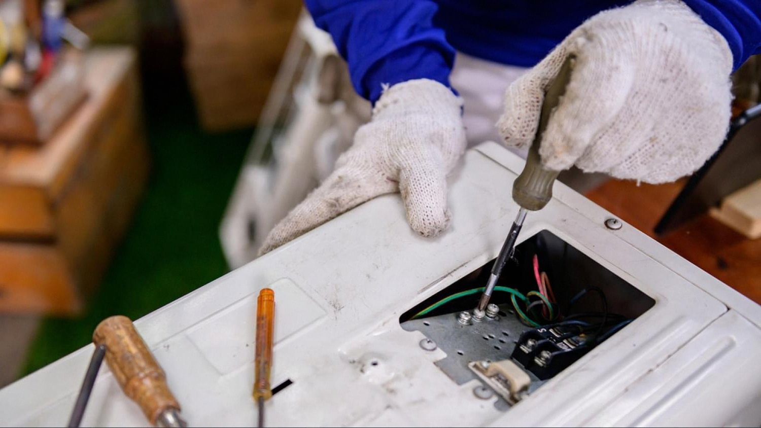 Technician in gloves repairing wiring inside a home appliance during a Dubai villa maintenance visit