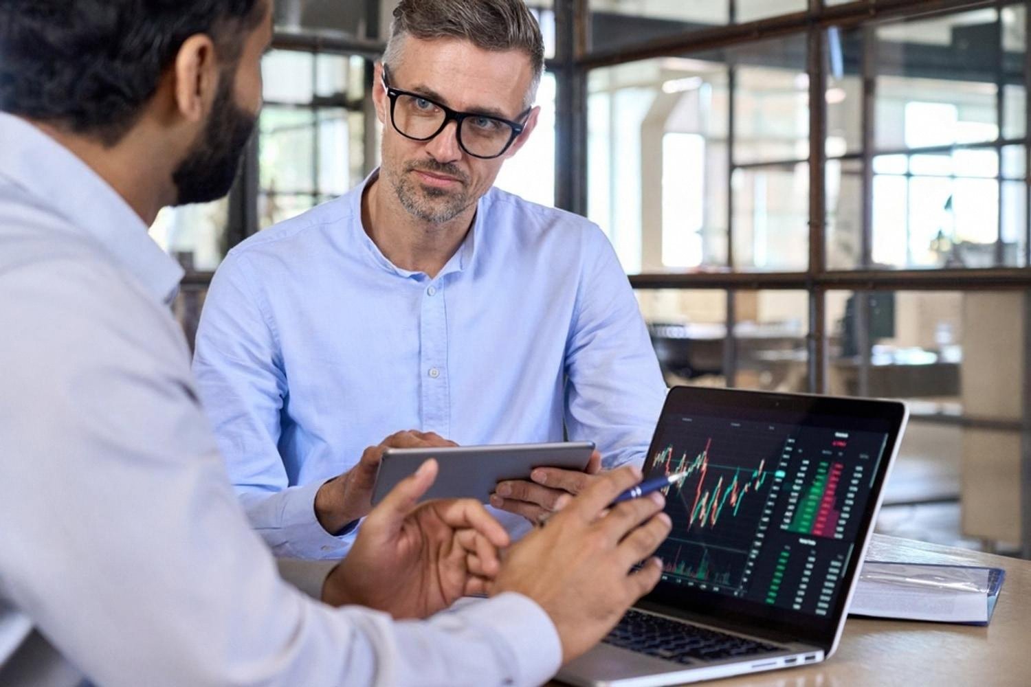 Business advisor discussing risk analysis charts with a client on a laptop in a Dubai office